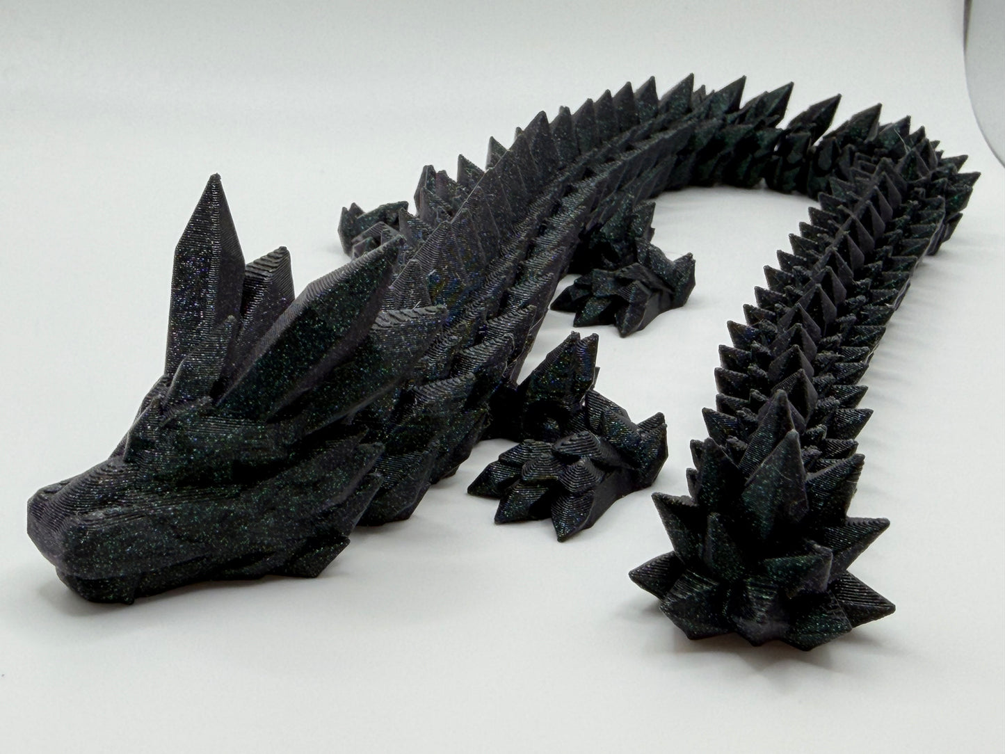 A fully articulated 18-inch 3D printed Crystal Dragon figure in dark green sparkly PLA, featuring crystal-shaped spikes and a segmented, poseable body.